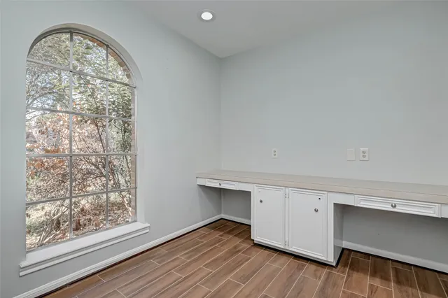 a view of an empty room with chandelier fan and wooden floor