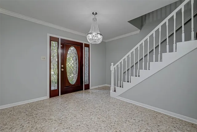 an empty room with wooden floor chandelier and windows