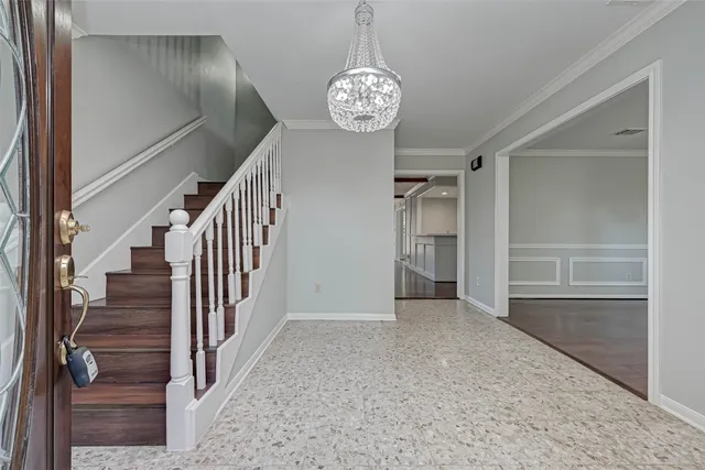 an empty room with wooden floor chandelier and windows