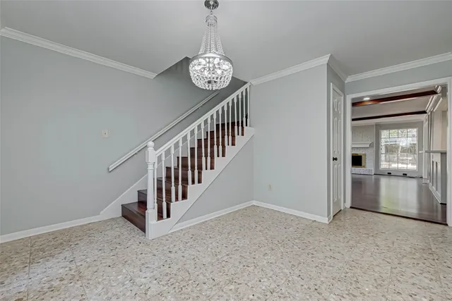 an empty room with wooden floor chandelier and windows