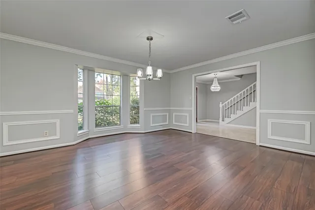 a view of an empty room with wooden floor and window