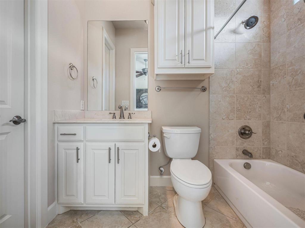 5001 Meridian Lane, Unit 2103 Addison, TX 75001 - Photo 21 of 26 Bathroom featuring a white vanity with a light-colored countertop, ceramic tile flooring, a built-in bathtub with tiled surround, and an overhead storage cabinet