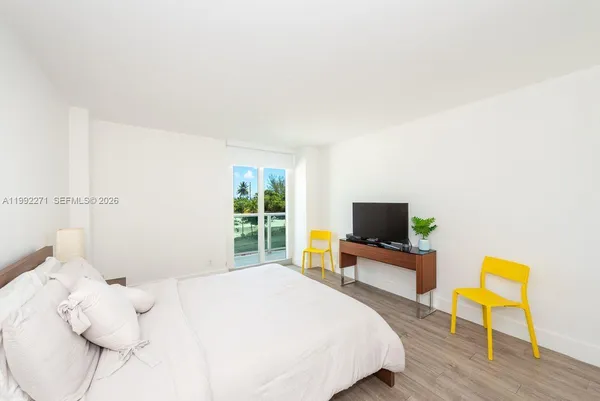 a bedroom with a bed and a flat tv screen on the dresser