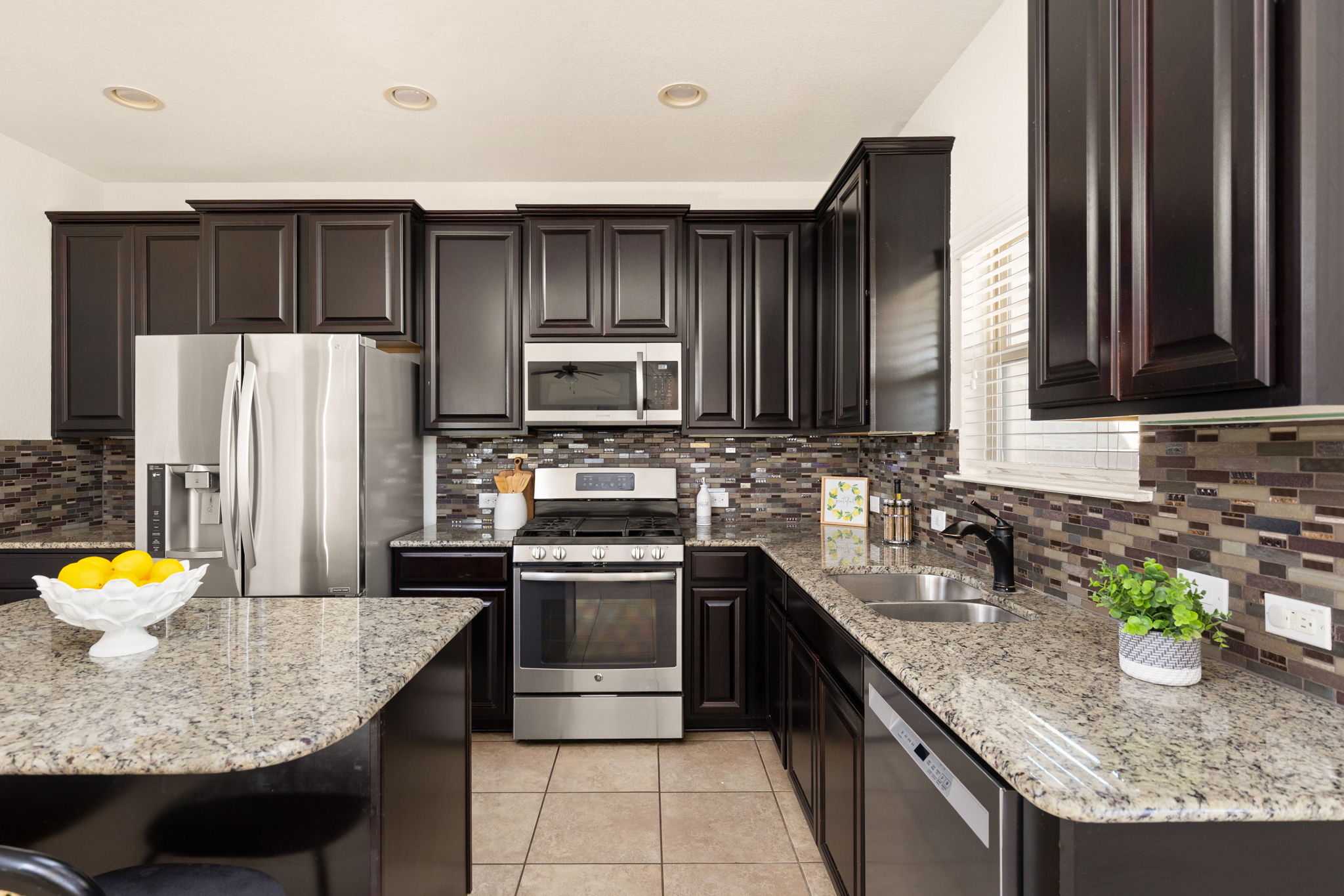 2400 Leonards Pass Leander, TX 78641 - Photo 17 of 40 A well-appointed kitchen showcasing dark wood cabinetry, a granite island, and tiled backsplash.