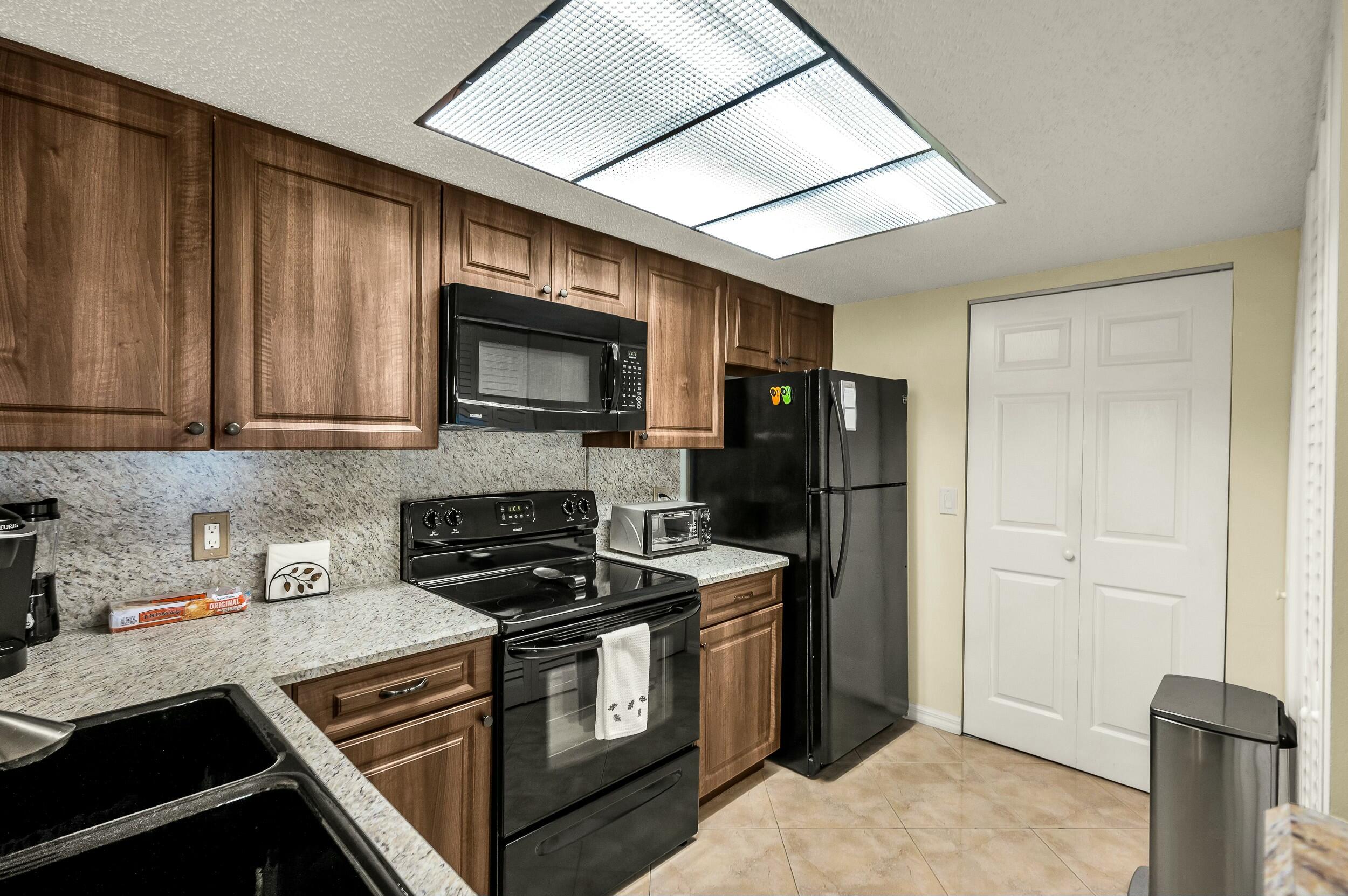 5031 Wiles Road, Unit 107 Coconut Creek, FL 33073 - Photo 11 of 22 a kitchen with stainless steel appliances granite countertop a stove and a refrigerator