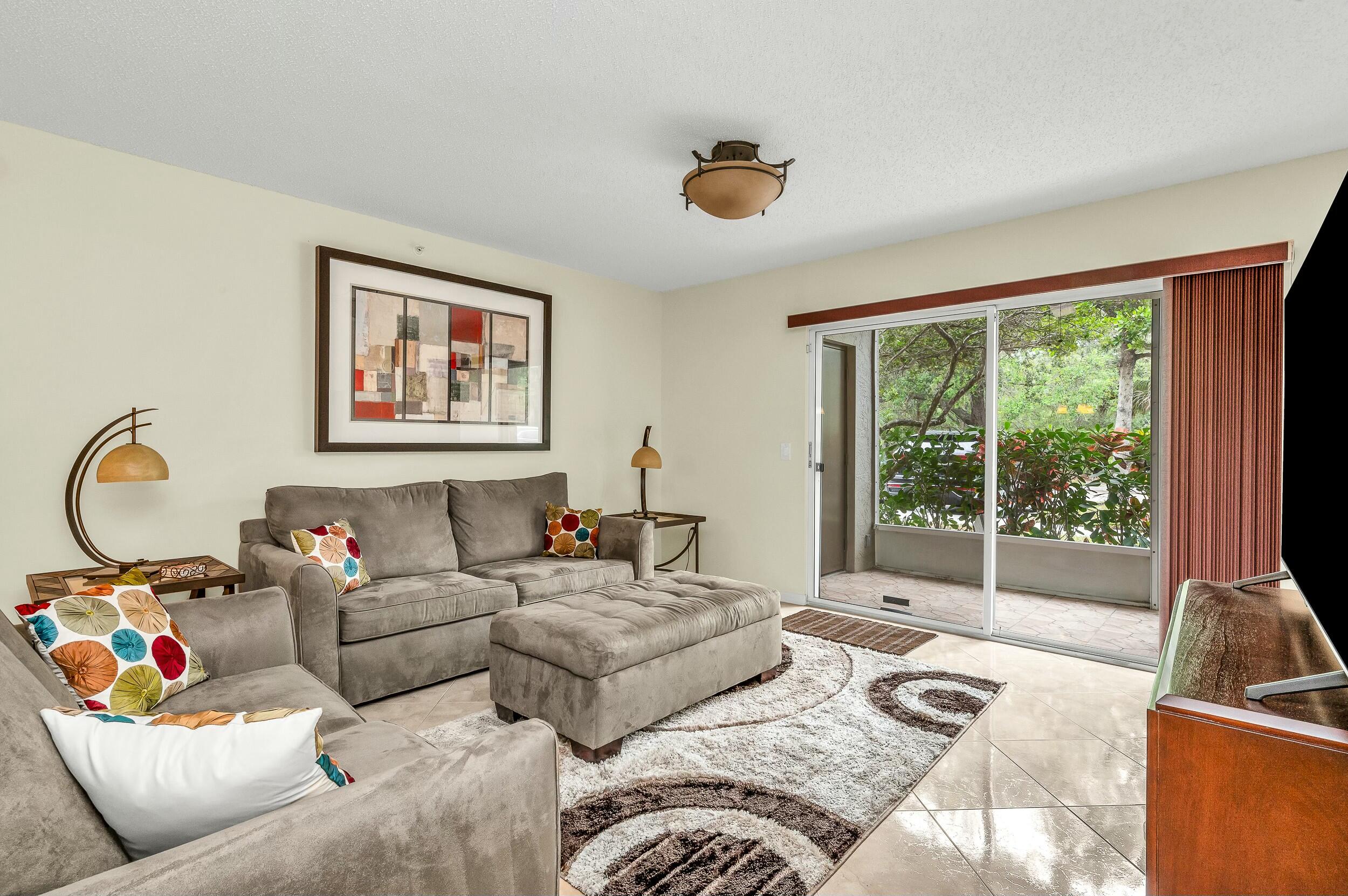 5031 Wiles Road, Unit 107 Coconut Creek, FL 33073 - Photo 13 of 22 a living room with furniture and a floor to ceiling window