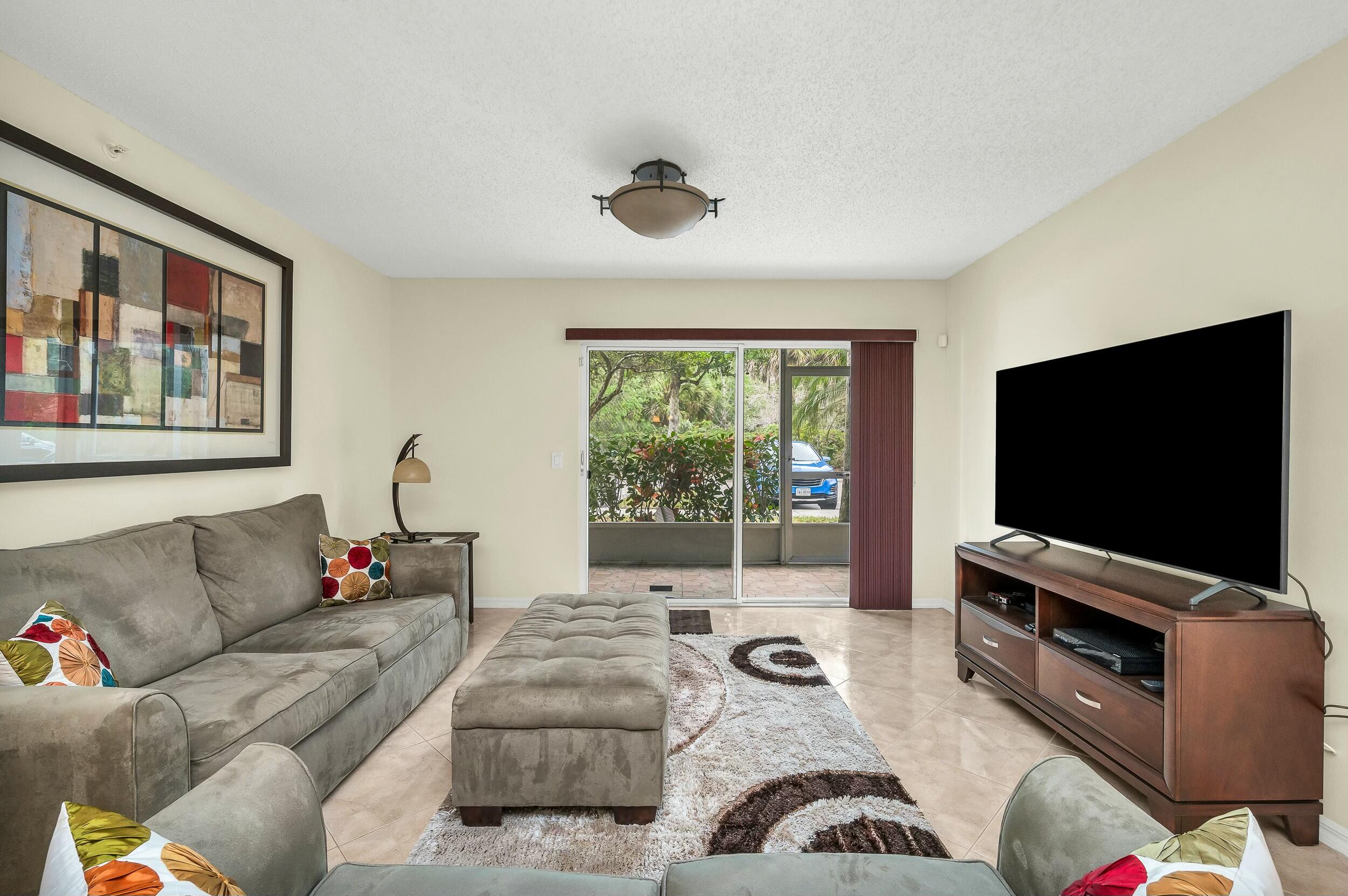5031 Wiles Road, Unit 107 Coconut Creek, FL 33073 - Photo 14 of 22 a living room with furniture and a flat screen tv
