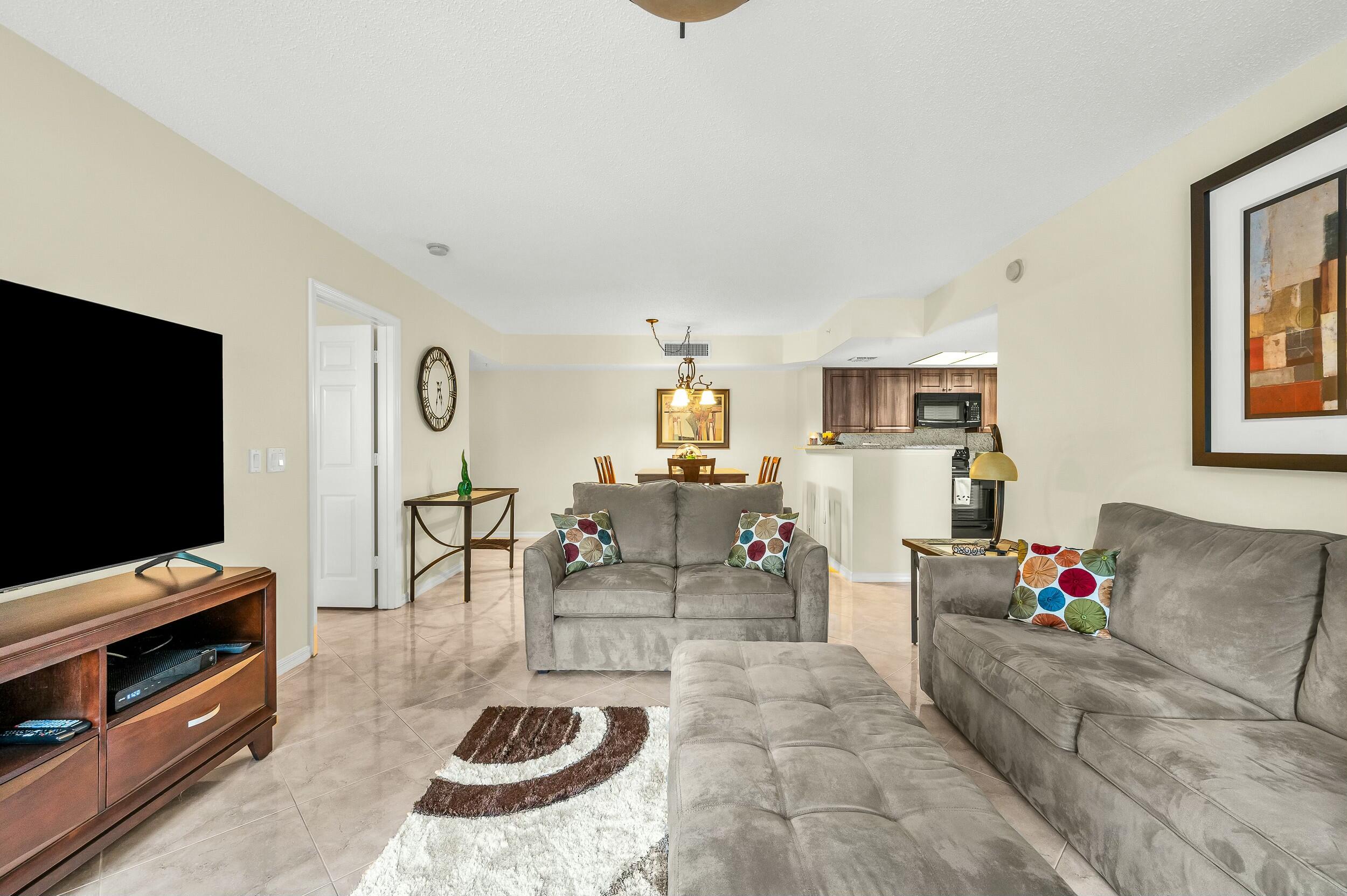 5031 Wiles Road, Unit 107 Coconut Creek, FL 33073 - Photo 16 of 22 a living room with furniture and a flat screen tv