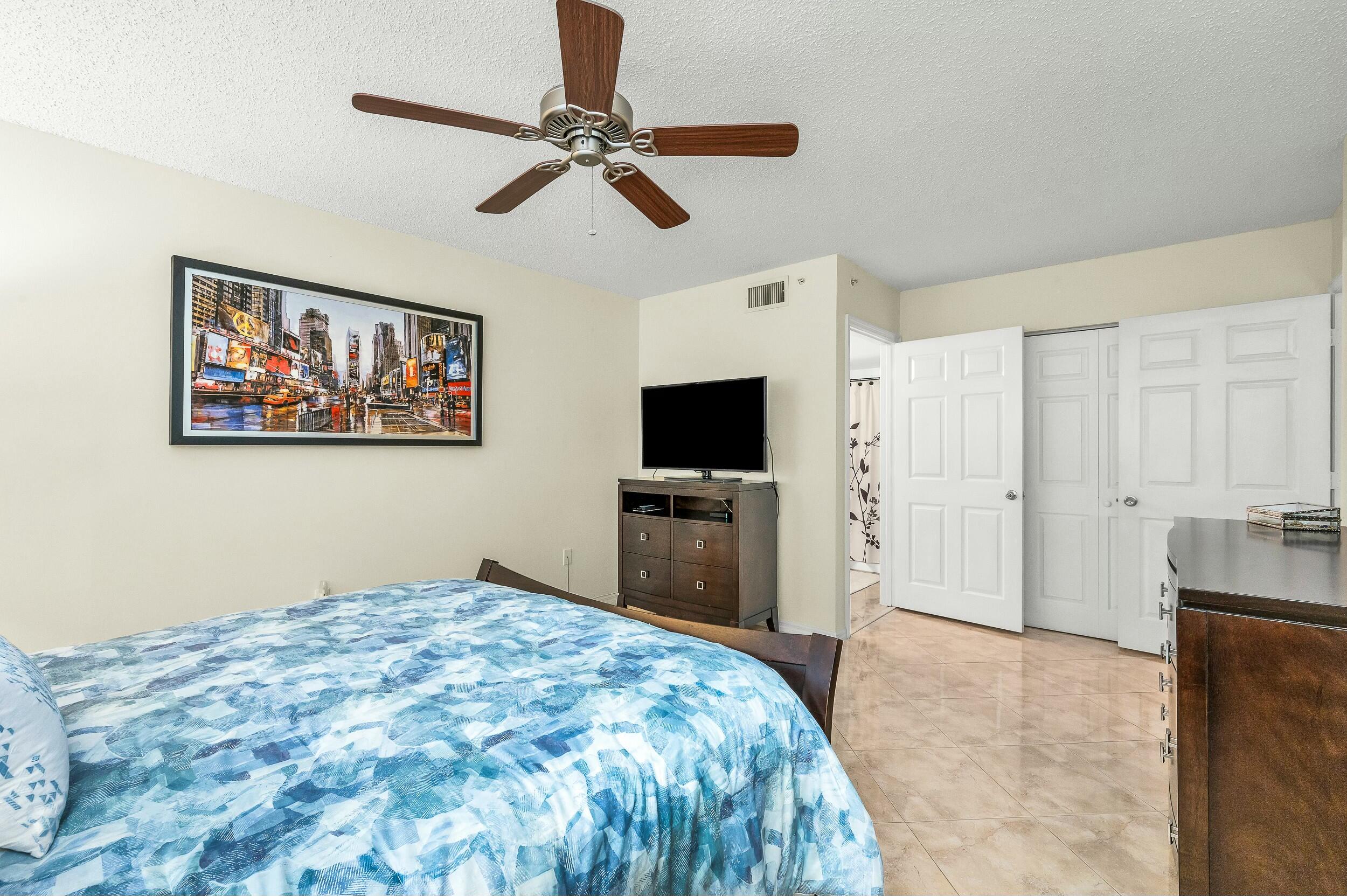 5031 Wiles Road, Unit 107 Coconut Creek, FL 33073 - Photo 3 of 22 a bedroom with a bed and a flat screen tv