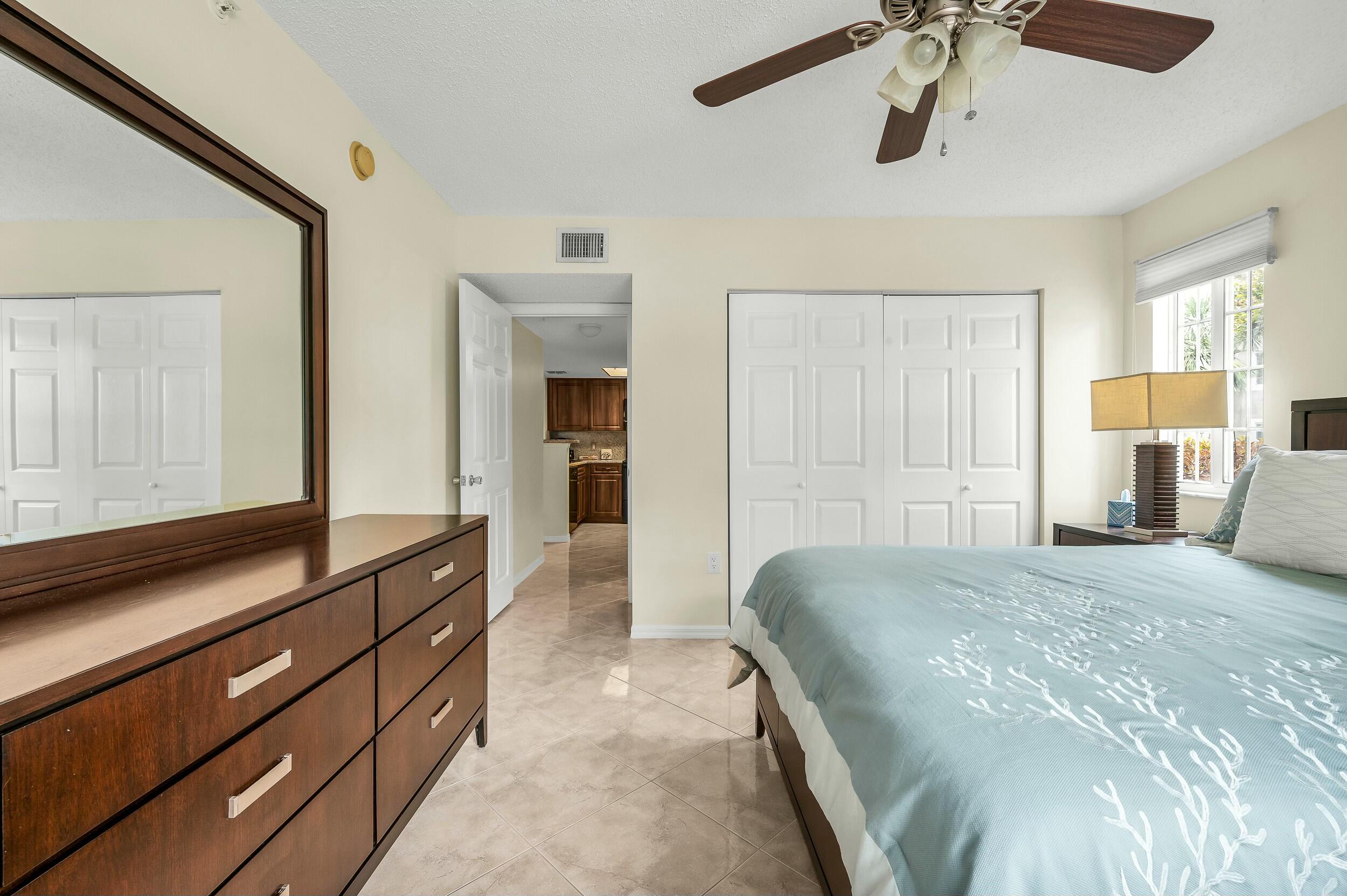 5031 Wiles Road, Unit 107 Coconut Creek, FL 33073 - Photo 7 of 22 a spacious bedroom with a bed and a dresser