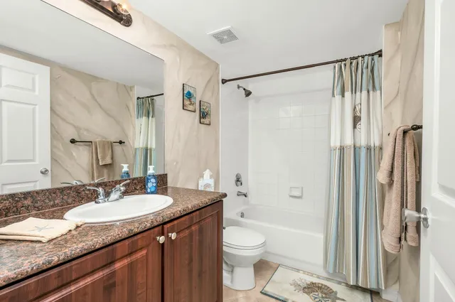 a bathroom with a granite countertop sink toilet and shower