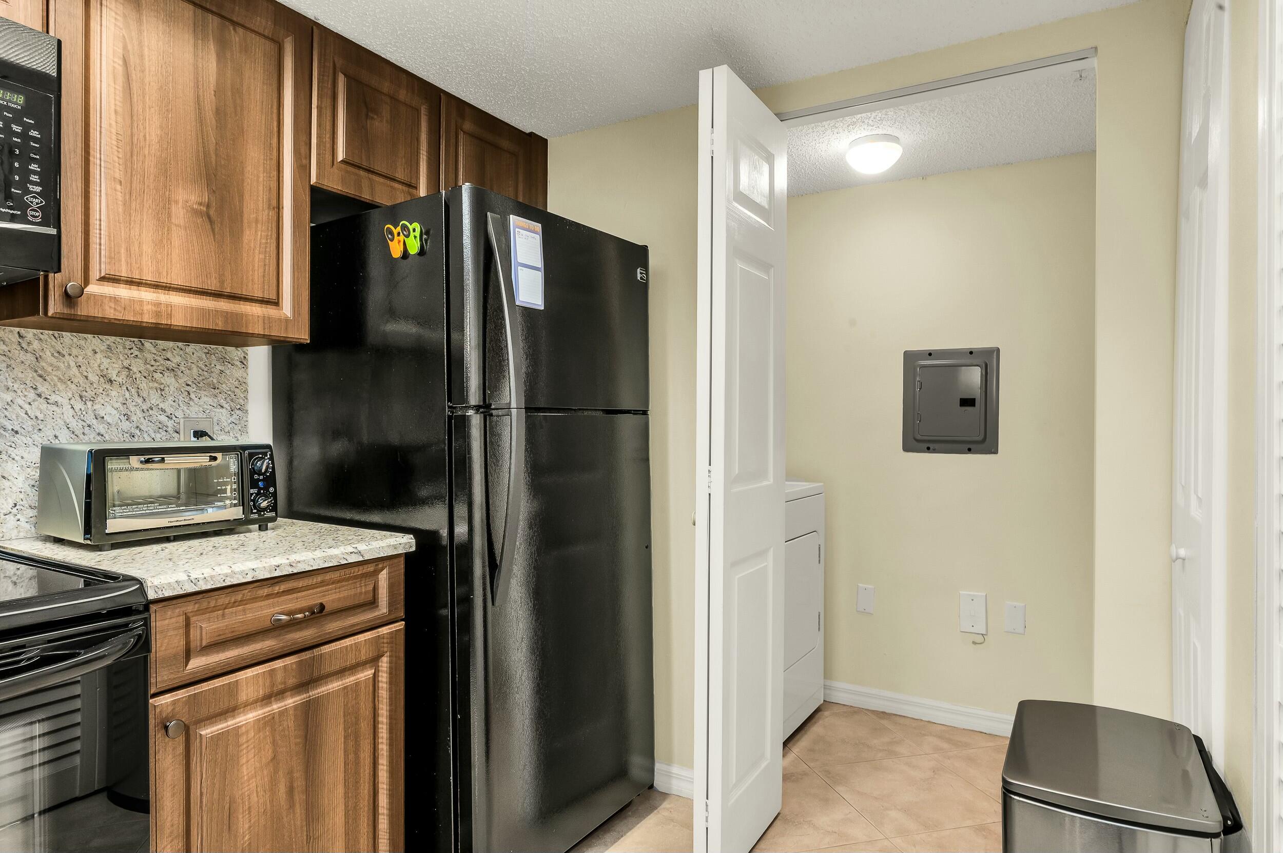 5031 Wiles Road, Unit 107 Coconut Creek, FL 33073 - Photo 9 of 22 a kitchen with a refrigerator and cabinets