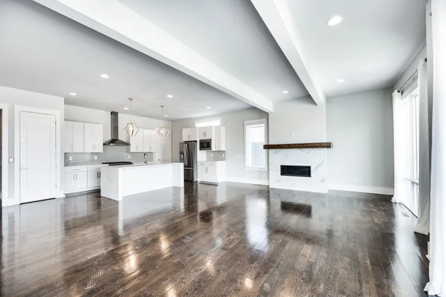 a kitchen with stainless steel appliances granite countertop a sink a stove a refrigerator and white cabinets with wooden floor