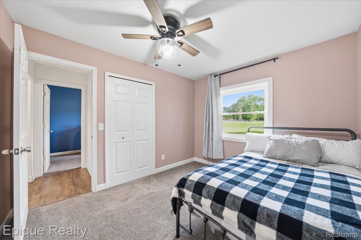 12272 East Mt Morris Road Davison, MI 48423 - Photo 17 of 39 Carpeted room featuring a ceiling fan with light fixture, white bi-fold closet doors, and a window with a green outdoor scenery