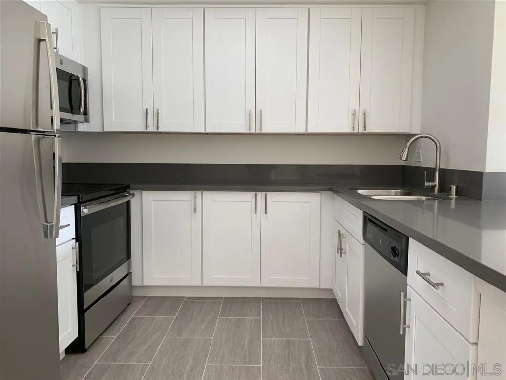 6064 Rancho Mission Road, Unit 448 San Diego, CA 92108 - Photo 1 of 15 a kitchen with granite countertop white cabinets and stainless steel appliances