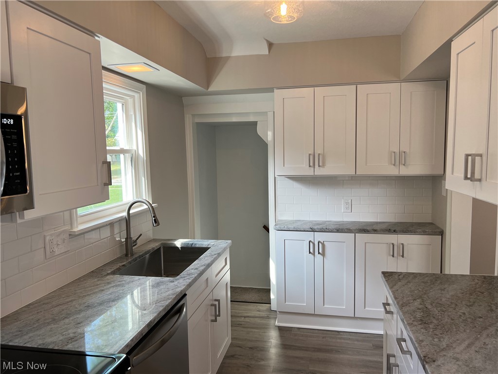 1609 Lyndhurst Road Lyndhurst, OH 44124 - Photo 13 of 34 Kitchen with appliances with stainless steel finishes, hardwood flooring, backsplash, and white cabinetry