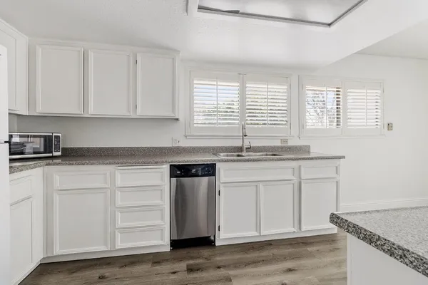a kitchen with granite countertop white cabinets and a sink