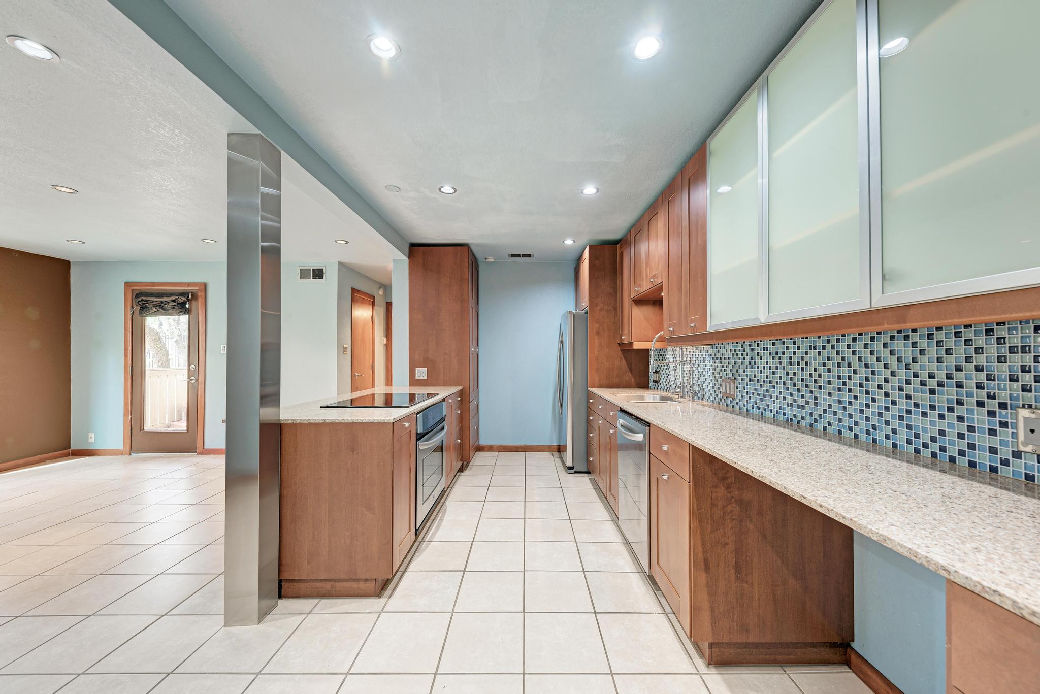 8210 Bent Tree Road, Unit 138 Austin, TX 78759 - Photo 12 of 23 Kitchen with wood finish cabinetry, light stone counters, backsplash, light tile patterned floors, and recessed lighting