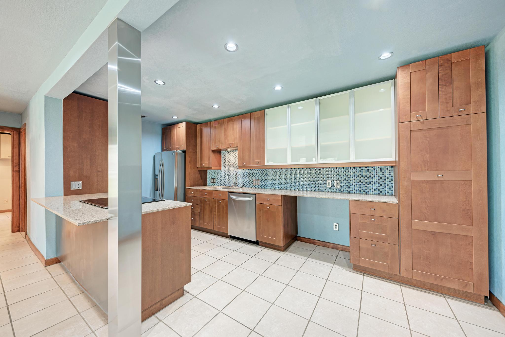 8210 Bent Tree Road, Unit 138 Austin, TX 78759 - Photo 13 of 23 Kitchen featuring wood finish cabinetry, glass fronted cabinets, a peninsula, light stone countertops, and recessed lighting
