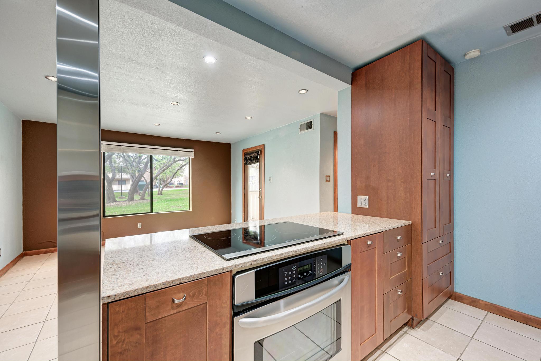 8210 Bent Tree Road, Unit 138 Austin, TX 78759 - Photo 17 of 23 Kitchen with wood finish cabinetry, stainless steel appliances, light stone counters, light tile patterned floors, and recessed lighting