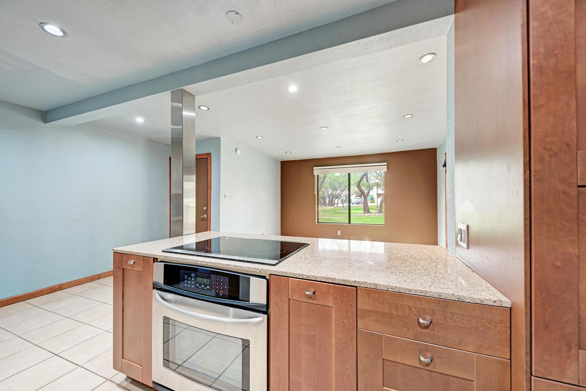 8210 Bent Tree Road, Unit 138 Austin, TX 78759 - Photo 18 of 23 Kitchen featuring oven, light stone countertops, a peninsula, black electric cooktop, and recessed lighting