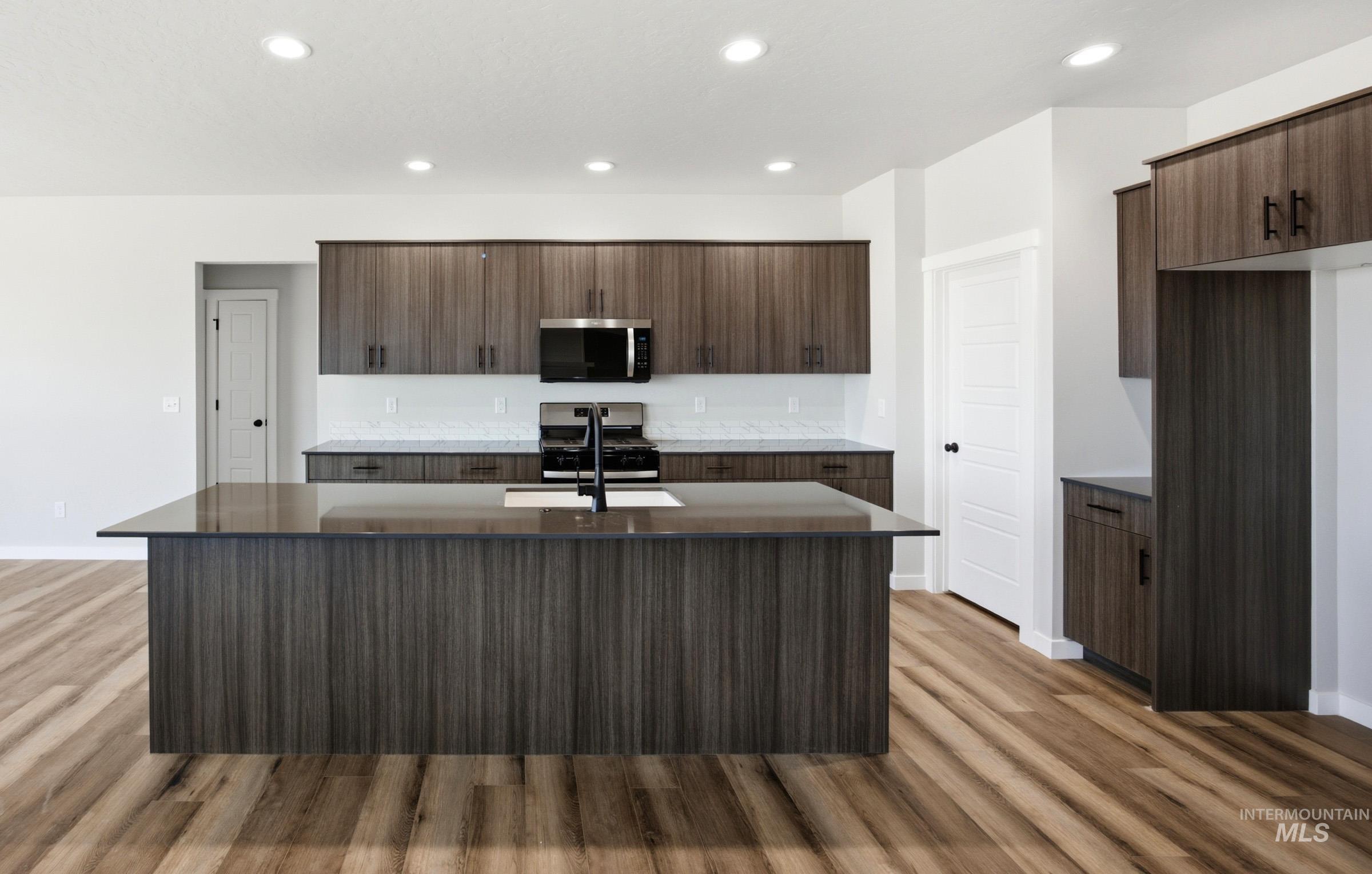 4344 East Rincon Drive Meridian, ID 83642 - Photo 3 of 26 Kitchen featuring a large island with sink, wood-finish cabinetry, stainless steel appliances, and wood-finish flooring