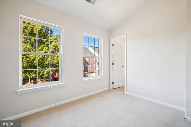 a view of empty room with wooden floor and kitchen view