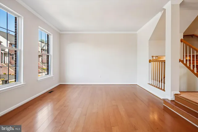 a view of an empty room with window wooden floor and a chandelier