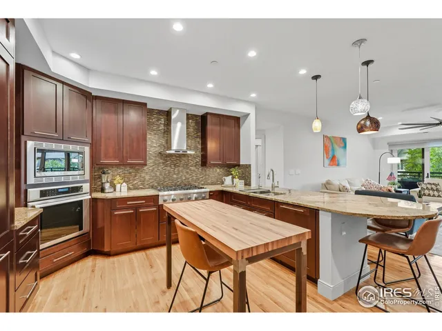 a kitchen with stainless steel appliances granite countertop wooden cabinets a stove a sink and a refrigerator