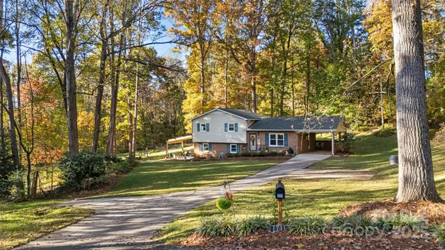 a view of a house with a big yard and large trees