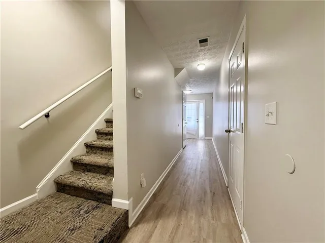 a view of a hallway with wooden floor and staircase