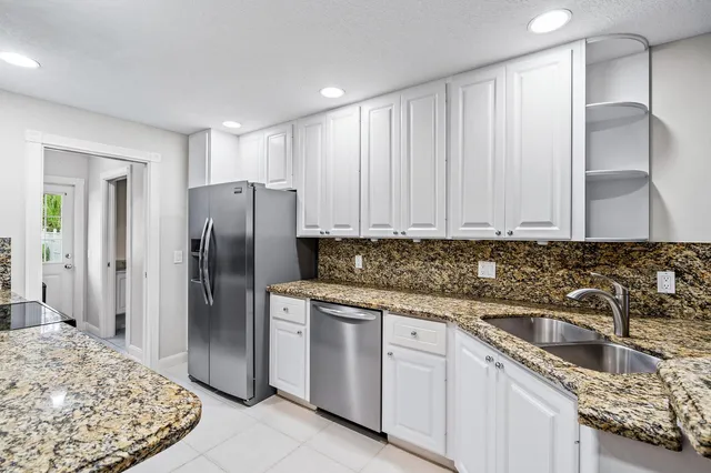 a kitchen with stainless steel appliances granite countertop a refrigerator and a sink