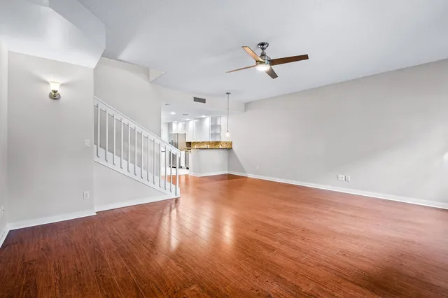 a view of a room with wooden floor a ceiling fan and windows