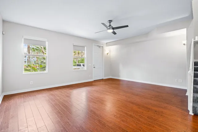 a view of empty room with wooden floor and fan