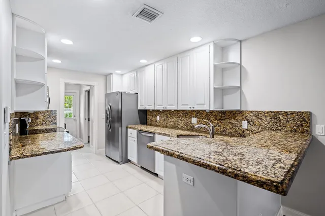 a kitchen with stainless steel appliances granite countertop a sink refrigerator and cabinets