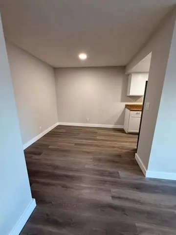 a view of an empty room with wooden floor and stairs