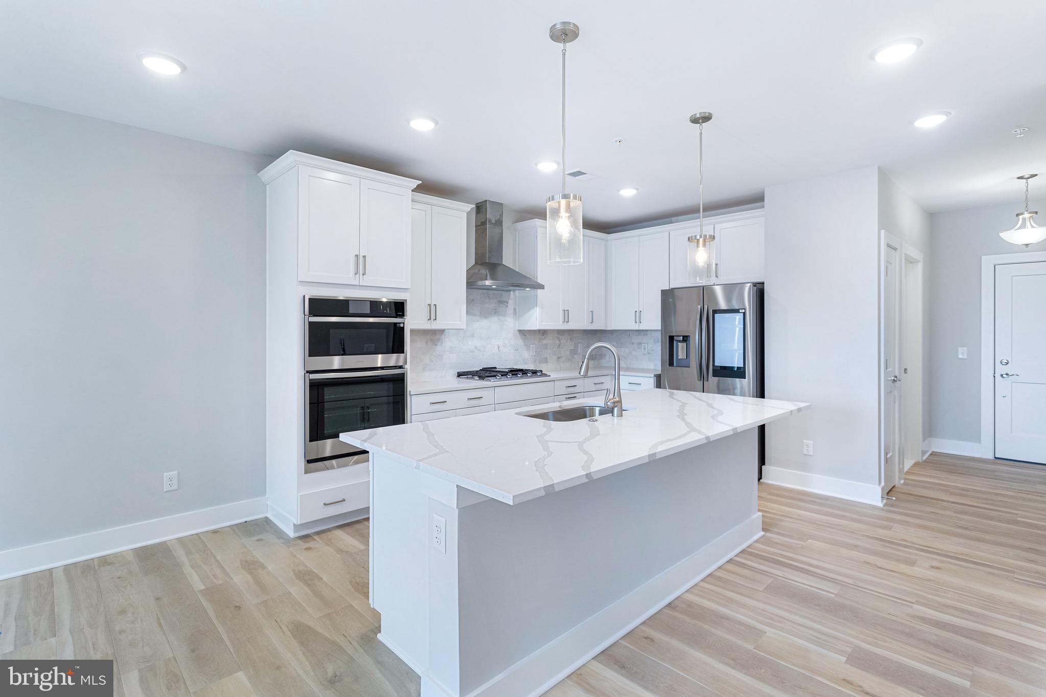 76 Old Mill Bottom Road North, Unit 308 Annapolis, MD 21409 - Photo 20 of 38 a large kitchen with stainless steel appliances kitchen island granite countertop a stove a sink a refrigerator and white cabinets with wooden floor