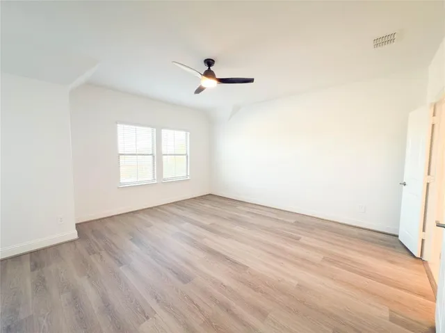 an empty room with wooden floor cabinet and windows