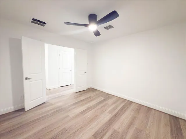an empty room with wooden floor and chandelier fan