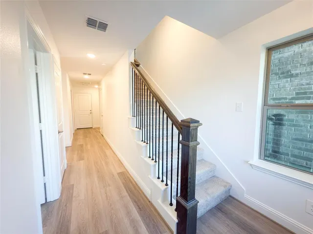 a view of a hallway with wooden floor and staircase