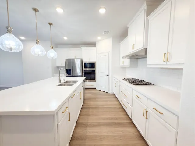 a large kitchen with kitchen island a stove a sink a center island and wooden floor