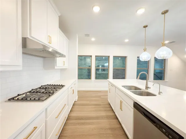 a large kitchen with stainless steel appliances granite countertop a sink and white cabinets