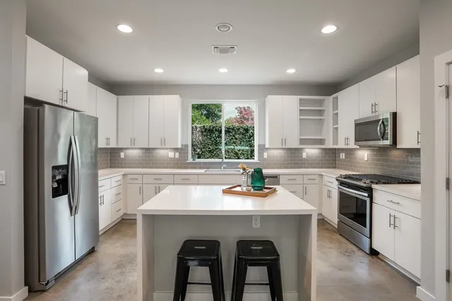 a kitchen that has a refrigerator a sink and white cabinets