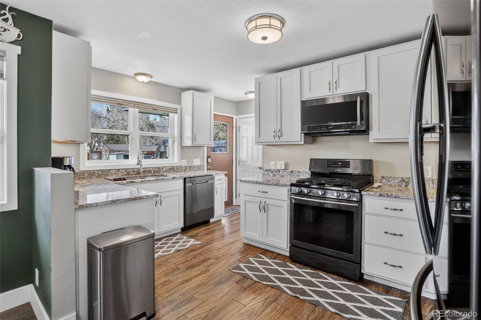 1313 Laredo Street Aurora, CO 80011 - Photo 4 of 23 a kitchen with stainless steel appliances a stove a sink and a refrigerator