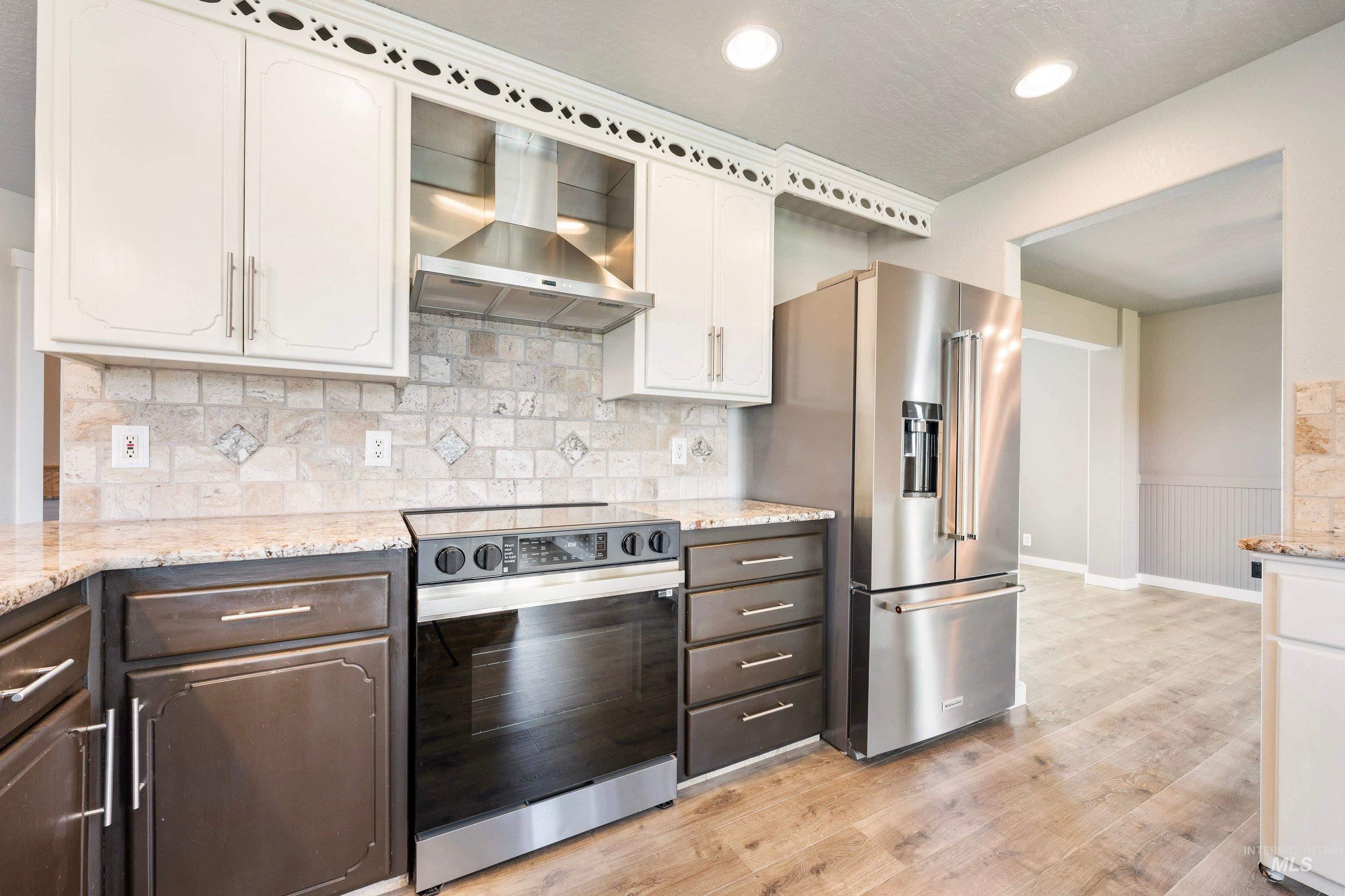7657 Track Road Nampa, ID 83686 - Photo 13 of 49 Kitchen featuring stainless steel appliances, dual-tone cabinetry, stone-finish countertops, a stone-tiled backsplash, and wood-finish flooring