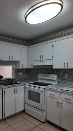 a kitchen with granite countertop white cabinets and white appliances