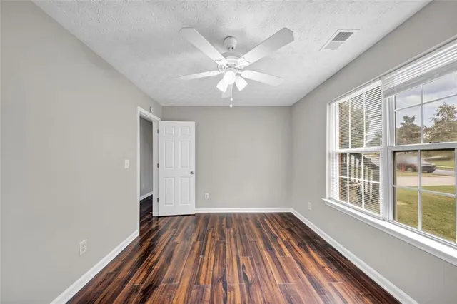 a living room with stainless steel appliances kitchen island hardwood floor and a ceiling fan