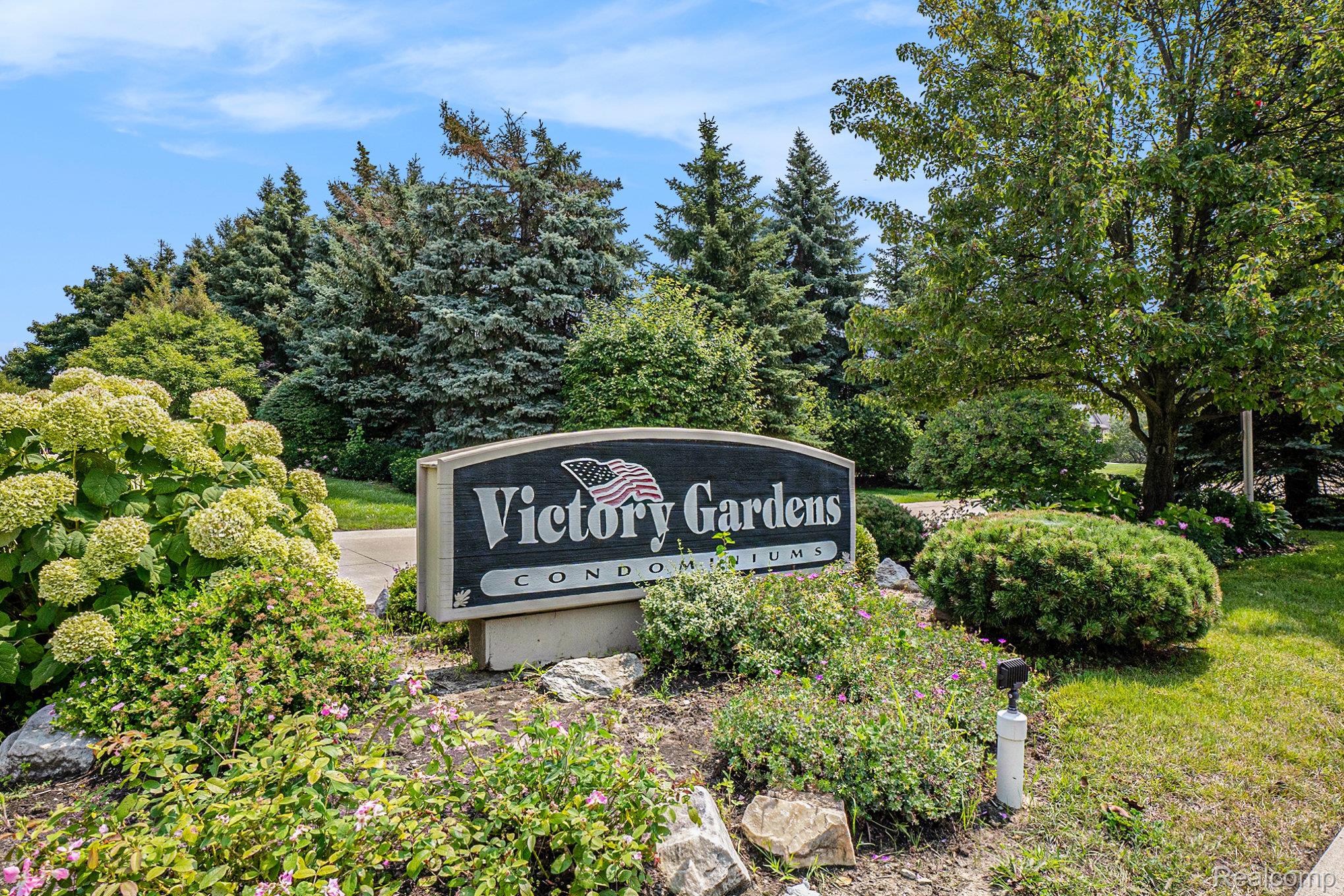 5477 Victory Circle Sterling Heights, MI 48310 - Photo 2 of 32 Victory Gardens Condominiums entrance sign amidst abundant landscaping