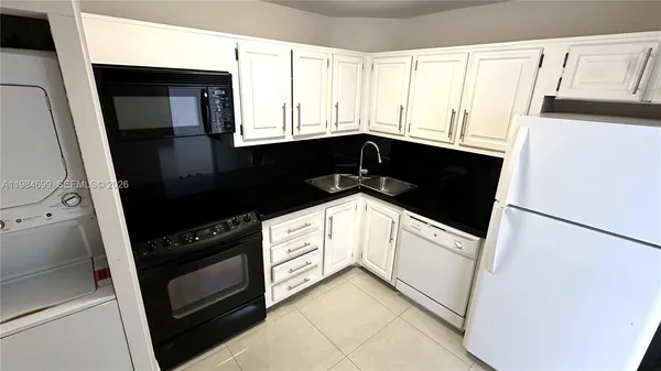 a kitchen with granite countertop white cabinets and black appliances