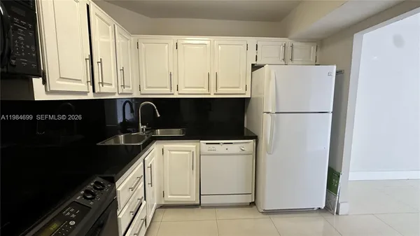 a kitchen with a refrigerator and white cabinets